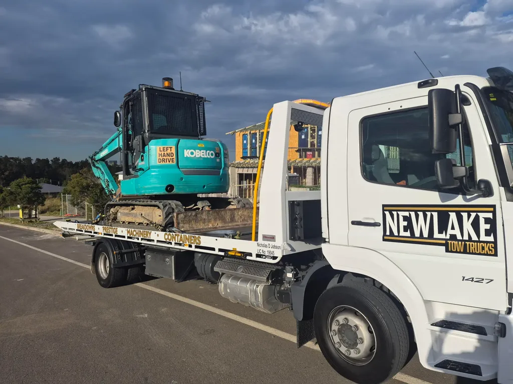 NewLake tow truck carrying a Kobelco mini excavator
