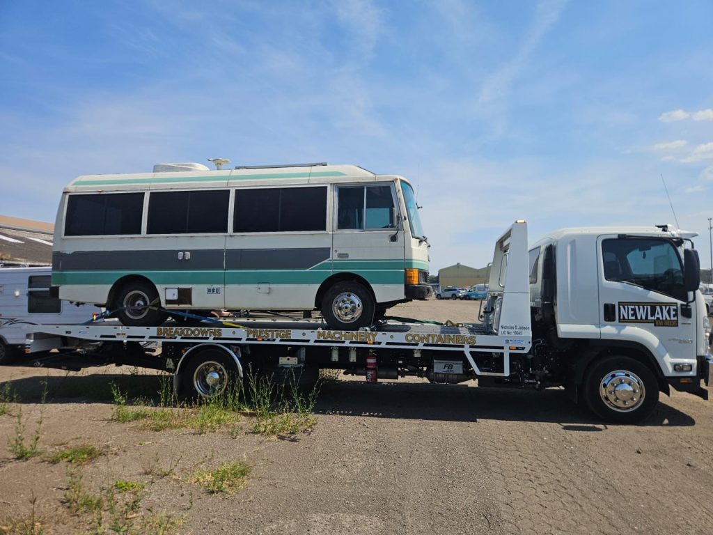 Newlake tow truck towing a small bus